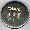 1979 09 Police fin costello black background larger round button.jpg